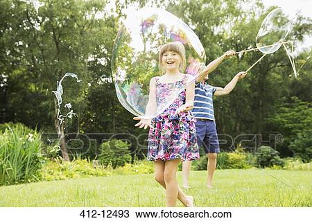 Children playing with bubbles in backyard View Large Photo Image Stock Image - Children playing with bubbles in backyard. Fotosearch