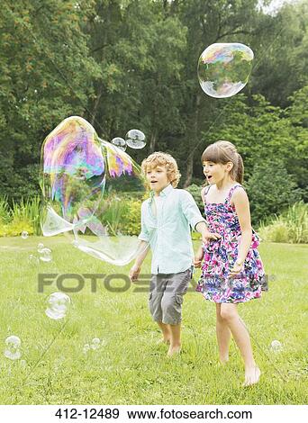 Children playing with bubbles in backyard View Large Photo Image Stock Photo - Children playing with bubbles in backyard. Fotosearch