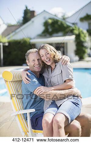 Couple sitting in lounge chair at poolside View Large Photo Image Stock Image - Couple sitting in lounge chair at poolside. Fotosearch