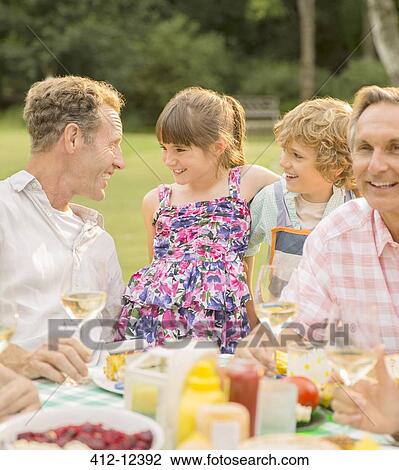 Family eating at table in backyard View Large Photo Image Stock Image - Family eating at table in backyard. Fotosearch