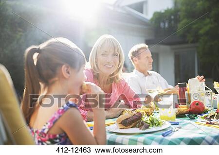 Stock Image - Family eating lunch at patio table. Fotosearch