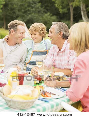 Family enjoying lunch at table in backyard View Large Photo Image Stock Photo - Family enjoying lunch at table in backyard. Fotosearch