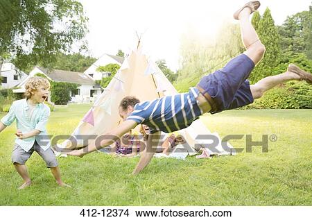 Picture - Family playing outside teepee in backyard. Fotosearch