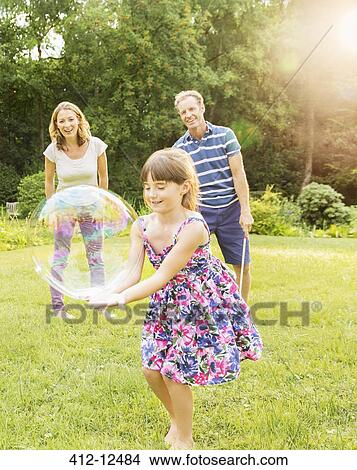 Picture - Family playing with bubbles in backyard. Fotosearch