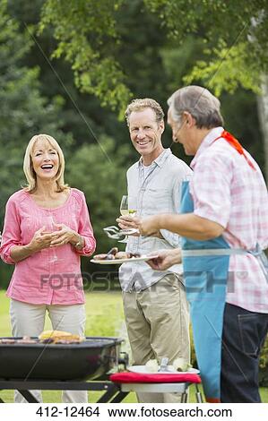 Picture - Family standing at barbecue in backyard. Fotosearch