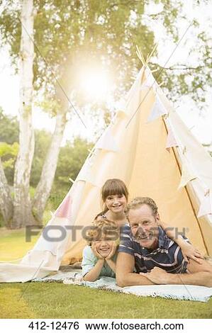 Stock Photograph - Father and children relaxing in teepee in backyard. Fotosearch