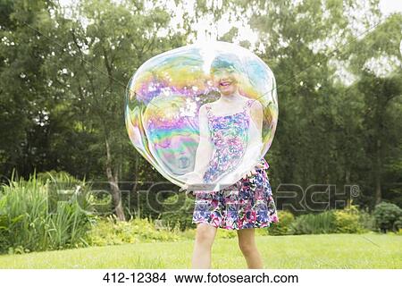 Picture - Father and daughter playing with large bubbles in backyard. Fotosearch