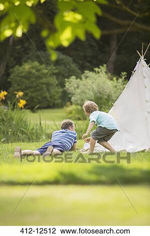Stock Image - Father and son laying outside teepee. Fotosearch