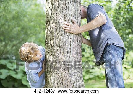 Father and son peeking around tree View Large Photo Image Stock Photo - Father and son peeking around tree. Fotosearch