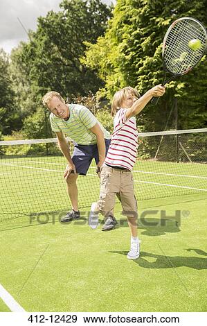 Stock Photo - Father and son playing tennis on grass court. Fotosearch