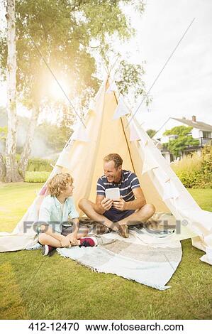 Father and son using digital tablet in teepee in backyard View Large Photo Image Stock Image - Father and son using digital tablet in teepee in backyard. Fotosearch