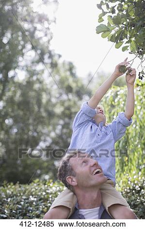 Stock Photography - Father carrying son on shoulders outdoors. Fotosearch