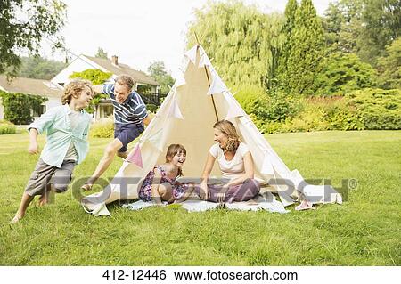 Father chasing son around teepee in backyard View Large Photo Image Stock Photograph - Father chasing son around teepee in backyard. Fotosearch