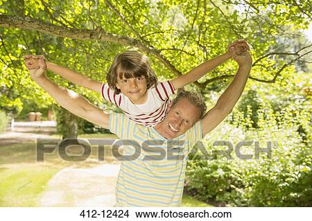 Picture - Father piggybacking son under tree. Fotosearch