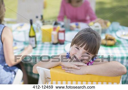 Girl smiling at table in backyard View Large Photo Image Stock Photo - Girl smiling at table in backyard. Fotosearch