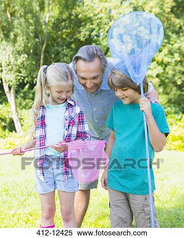 Stock Photography - Grandfather and grandchildren looking at butterfly in net. Fotosearch