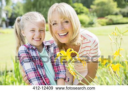Stock Photo - Grandmother and granddaughter smiling in garden. Fotosearch