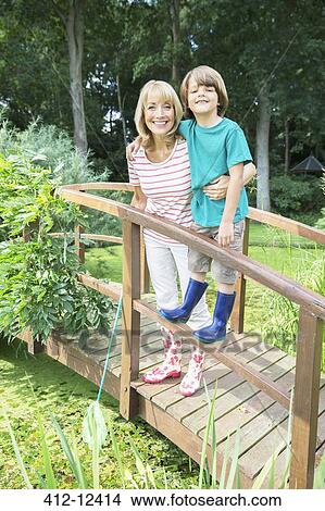 Picture - Grandmother and grandson smiling on wooden footbridge. Fotosearch