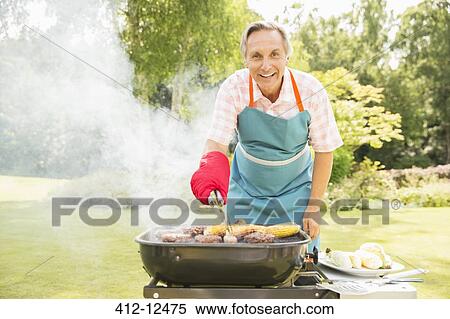 Man grilling food on barbecue in backyard View Large Photo Image Stock Photography - Man grilling food on barbecue in backyard. Fotosearch