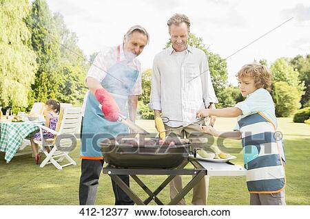 Men grilling meat on barbecue in backyard View Large Photo Image Stock Photo - Men grilling meat on barbecue in backyard. Fotosearch