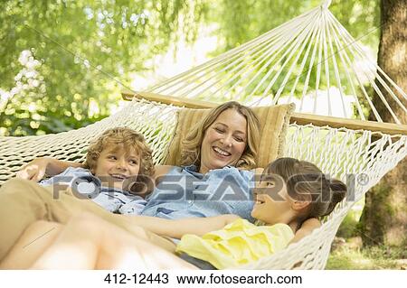 Stock Image - Mother and children relaxing together in hammock. Fotosearch