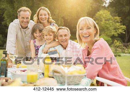 Stock Photography - Multi-generation family at table in backyard. Fotosearch