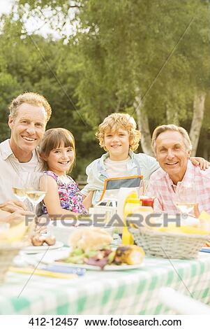 Multi-generation family eating lunch at table in backyard View Large Photo Image Stock Photo - Multi-generation family eating lunch at table in backyard. Fotosearch