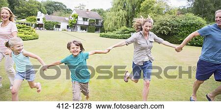 Stock Photo - Multi-generation family holding hands and running in backyard. Fotosearch