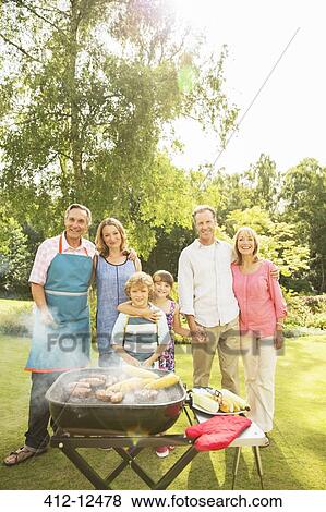 Stock Photo - Multi-generation family standing at barbecue in backyard. Fotosearch