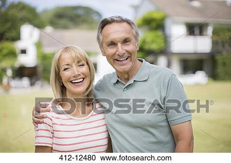Stock Image - Smiling senior couple hugging outdoors. Fotosearch