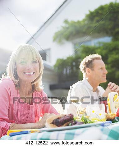 Smiling woman at table in backyard View Large Photo Image Stock Image - Smiling woman at table in backyard. Fotosearch