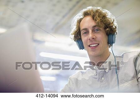 Businessman listening to headphones in office View Large Photo Image Picture - Businessman listening to headphones in office. Fotosearch