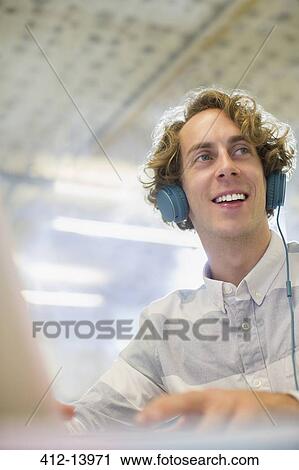 Businessman listening to headphones in office View Large Photo Image Stock Image - Businessman listening to headphones in office. Fotosearch