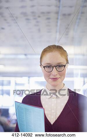 Businesswoman holding folder in office View Large Photo Image Stock Image - Businesswoman holding folder in office. Fotosearch