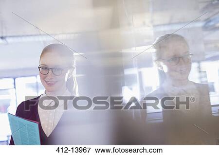 Stock Photo - Businesswoman holding folder in office. Fotosearch