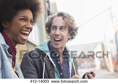 Stock Image - Couple laughing together on city street. Fotosearch