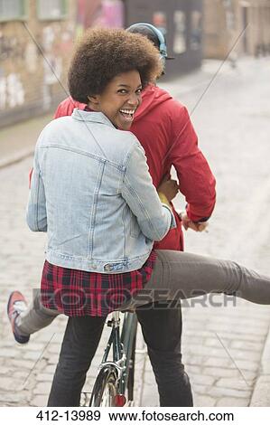 Stock Photo - Couple riding bicycle together on city street. Fotosearch