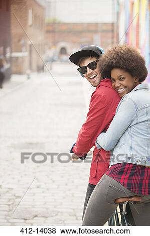 Stock Photo - Couple riding bicycle together on city street. Fotosearch