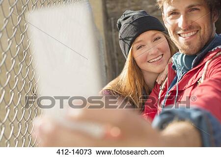 Couple taking self-portrait with camera phone next to chain link fence View Large Photo Image Stock Image - Couple taking self-portrait with camera phone next to chain link fence. Fotosearch