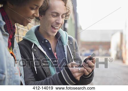 Stock Photo - Couple using cell phone on city street. Fotosearch