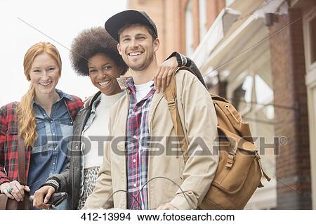 Picture - Friends smiling together on city street. Fotosearch