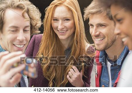 Friends taking self-portrait with camera phone outdoors View Large Photo Image Stock Photograph - Friends taking self-portrait with camera phone outdoors. Fotosearch