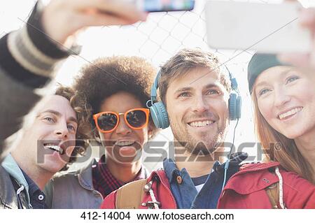 Picture - Friends taking self-portraits with camera phones outdoors. Fotosearch