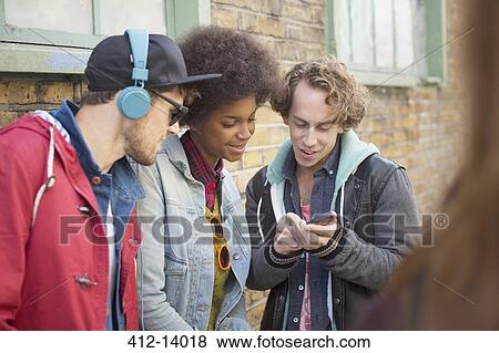 Friends using cell phone on city street View Large Photo Image Stock Photo - Friends using cell phone on city street. Fotosearch