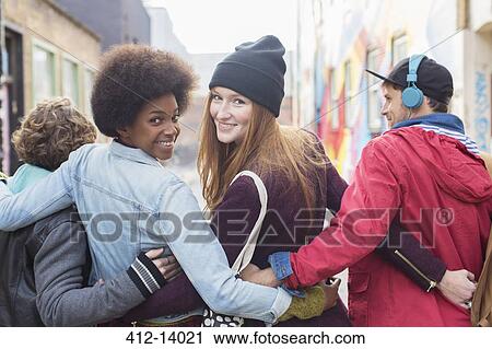 Stock Image - Friends walking together on city street. Fotosearch