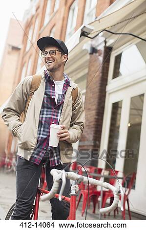 Man drinking coffee on bicycle on city street View Large Photo Image Picture - Man drinking coffee on bicycle on city street. Fotosearch
