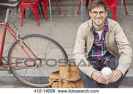 Stock Photo - Man drinking coffee on city street. Fotosearch