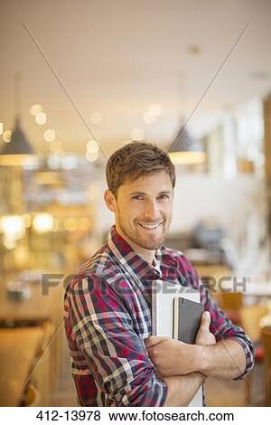 Man holding books in cafe View Large Photo Image Stock Photo - Man holding books in cafe. Fotosearch