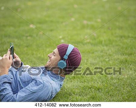 Man listening to headphones in park View Large Photo Image Stock Image - Man listening to headphones in park. Fotosearch