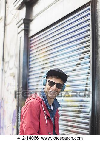 Man listening to headphones near graffiti wall View Large Photo Image Stock Photograph - Man listening to headphones near graffiti wall. Fotosearch